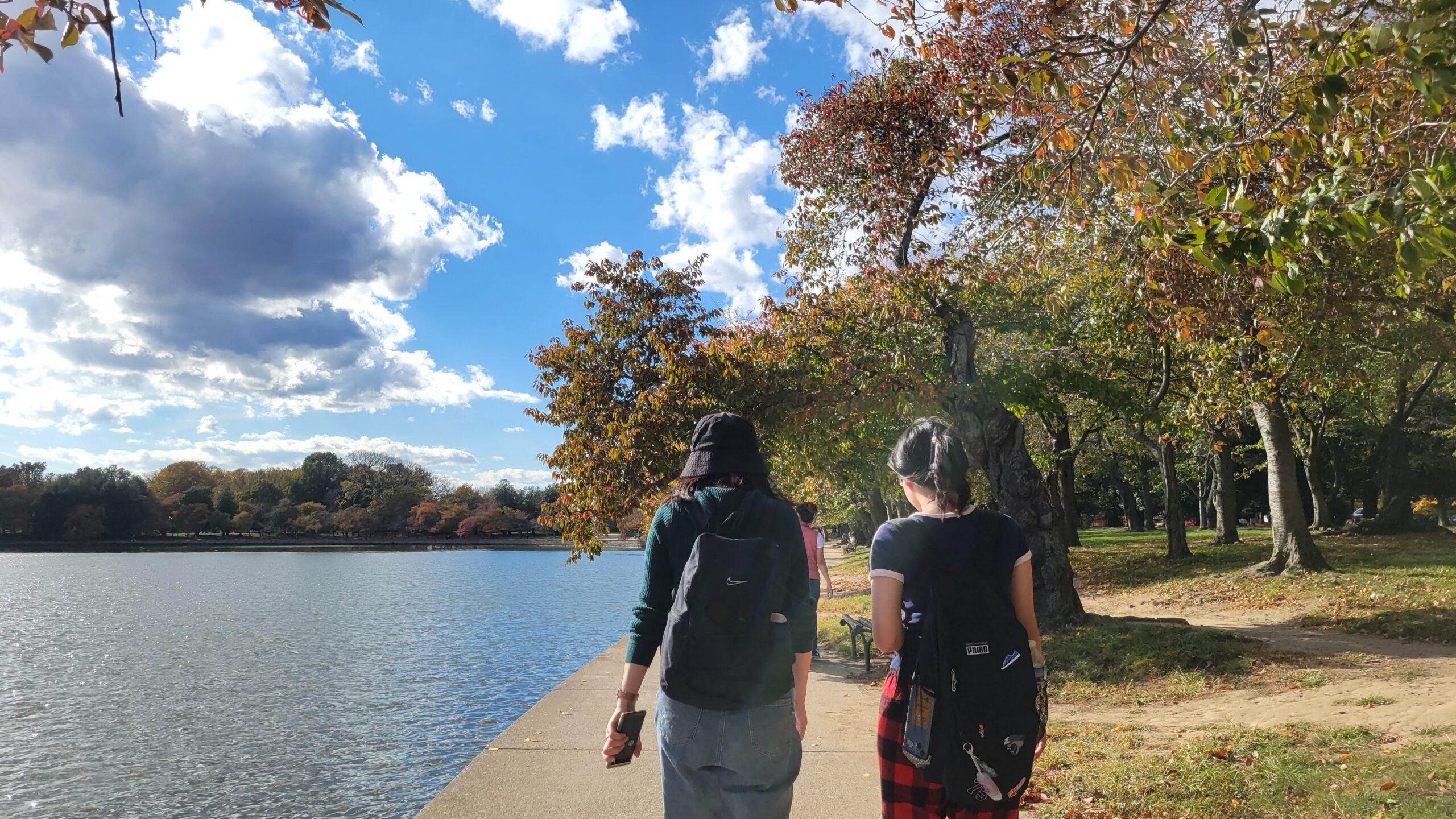 Two students walking beside a body of water